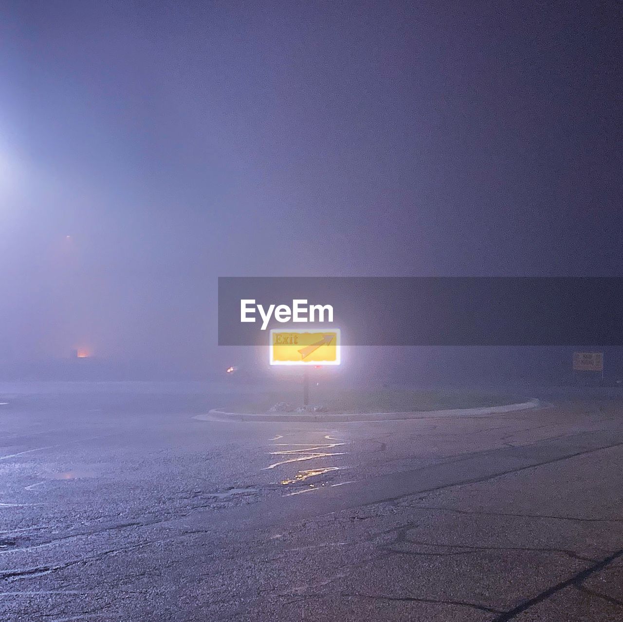Illuminated road sign at night during foggy weathered