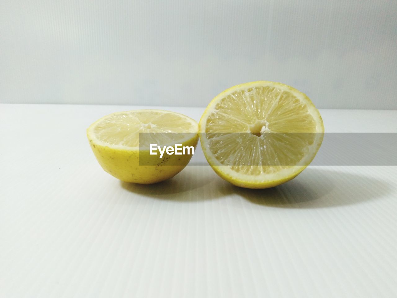 CLOSE-UP OF LEMON SLICE ON TABLE AGAINST WHITE BACKGROUND