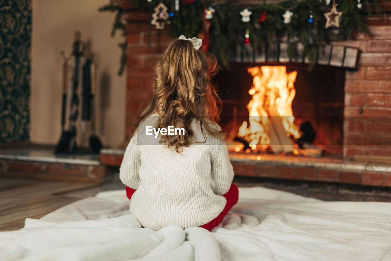 rear view of young woman standing by christmas tree at home