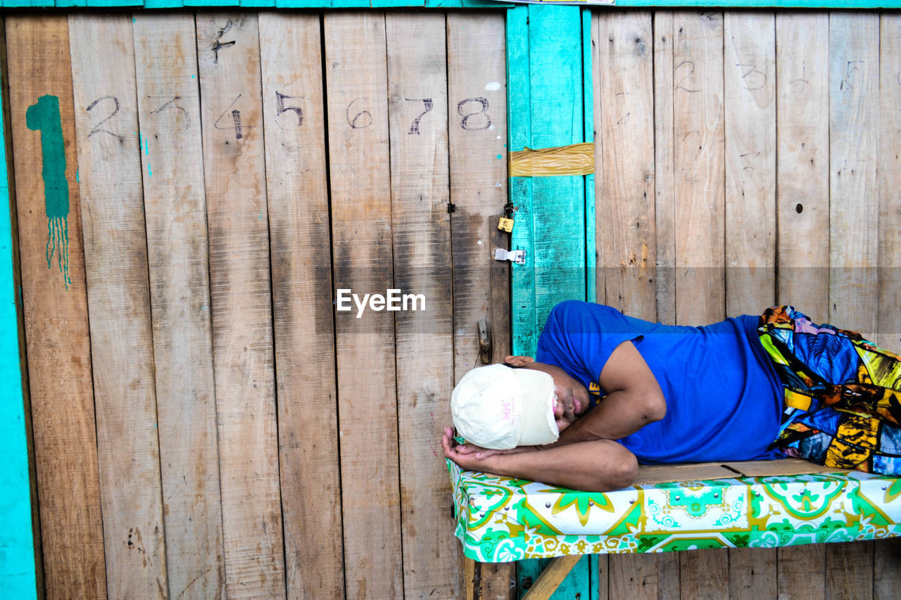 MID ADULT MAN LYING ON WALL