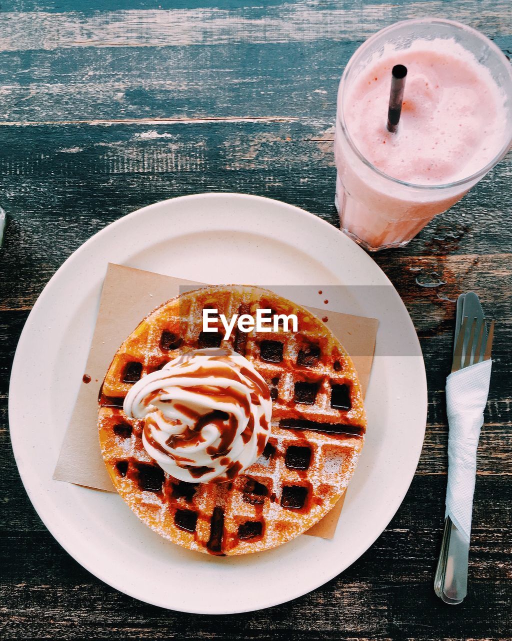 High angle view of fresh ice cream on waffle with chocolate sauce served in plate by smoothie