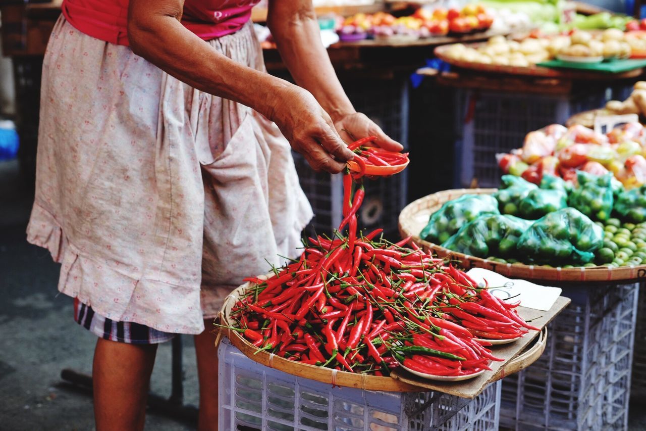 Man holding red chilies at market stall