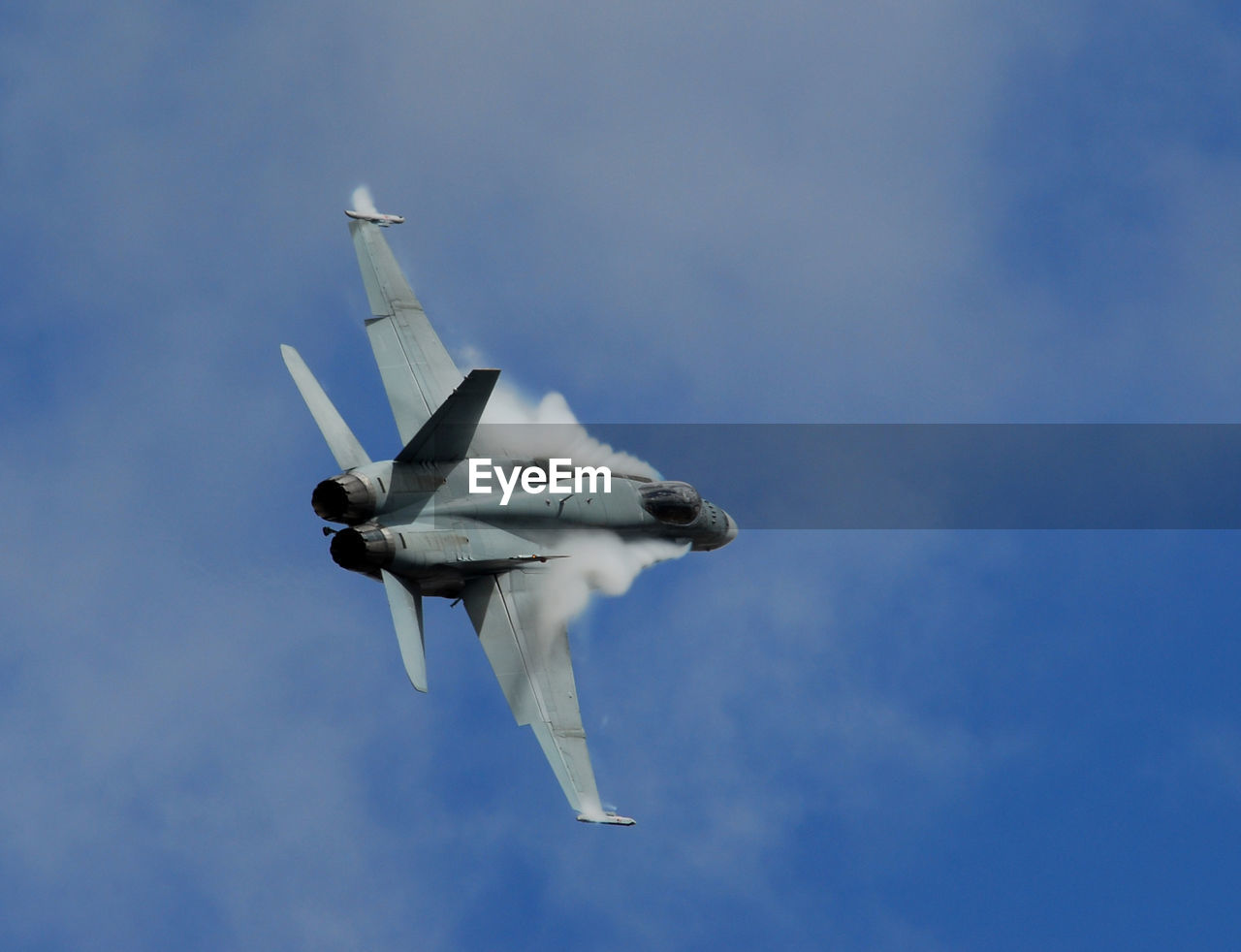 Low angle view of fighter plane flying against cloudy sky