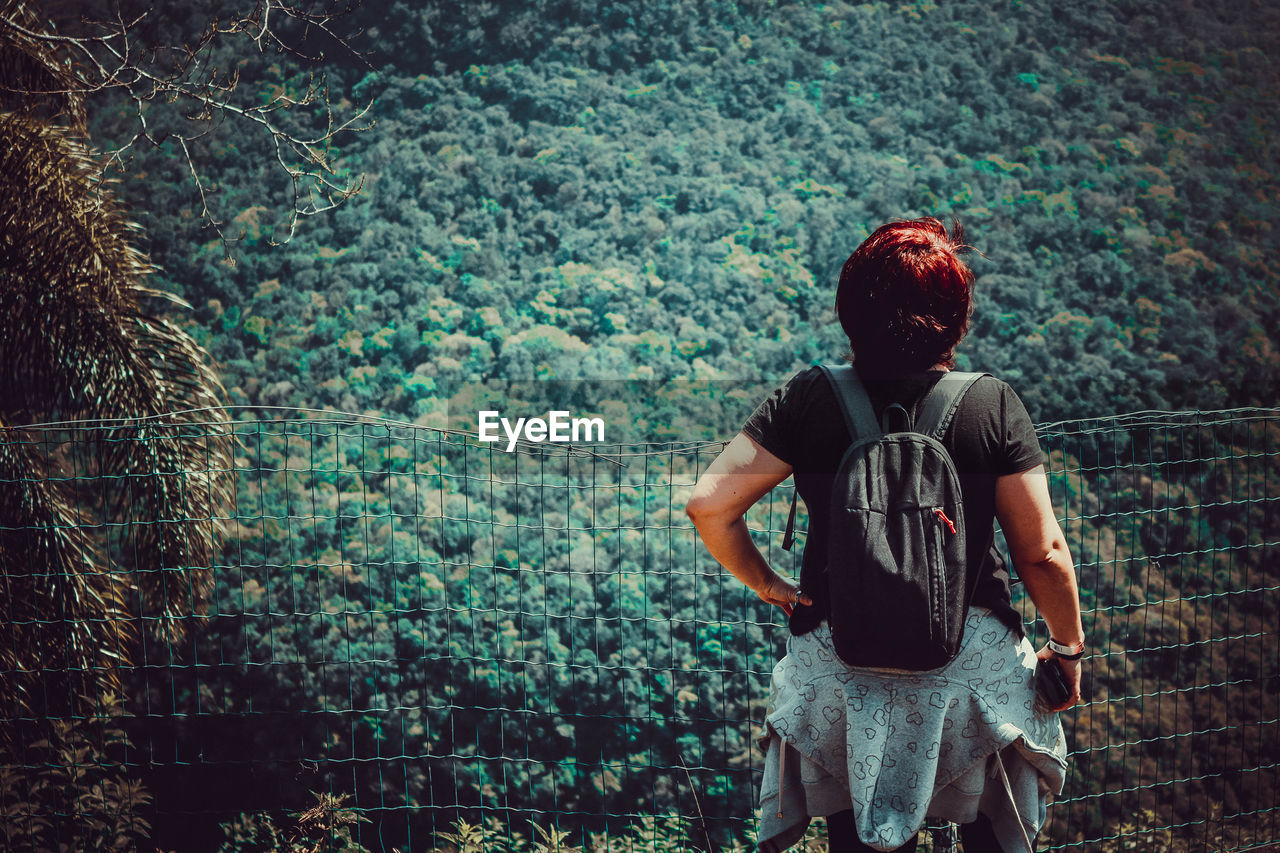 Rear view of woman wearing backpack standing in forest