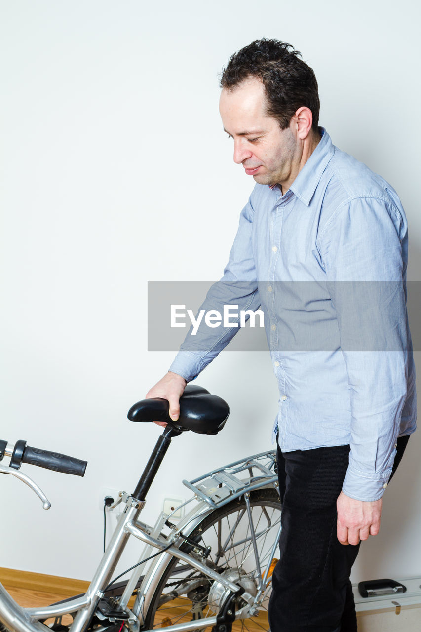 SIDE VIEW OF MAN LOOKING AT BICYCLE