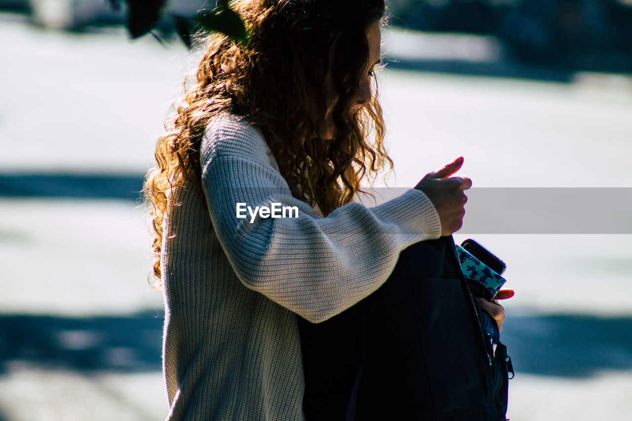 REAR VIEW OF WOMAN HOLDING LEAF IN PARK