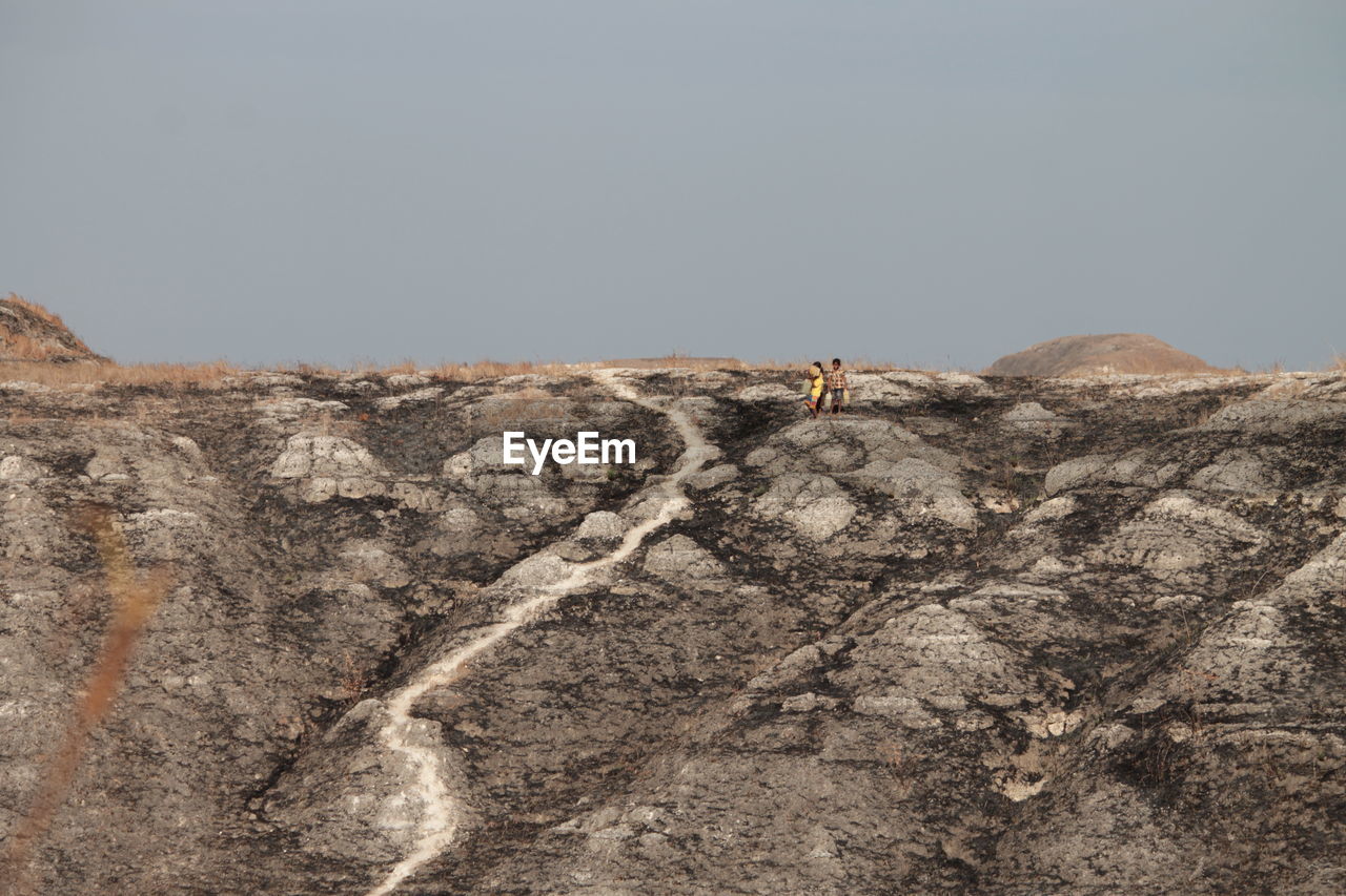 Siblings on landscape against sky