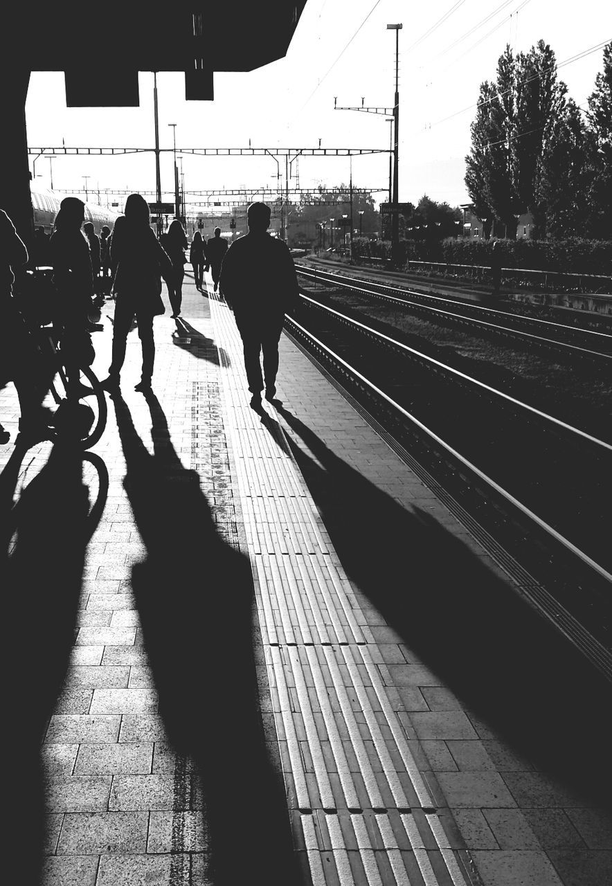 People on railroad station platform against sky during sunny day