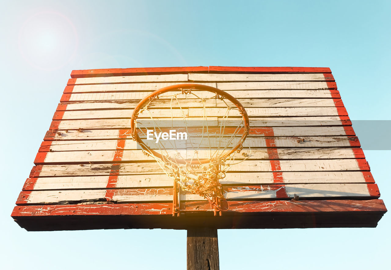 LOW ANGLE VIEW OF BASKETBALL HOOP AGAINST BLUE SKY
