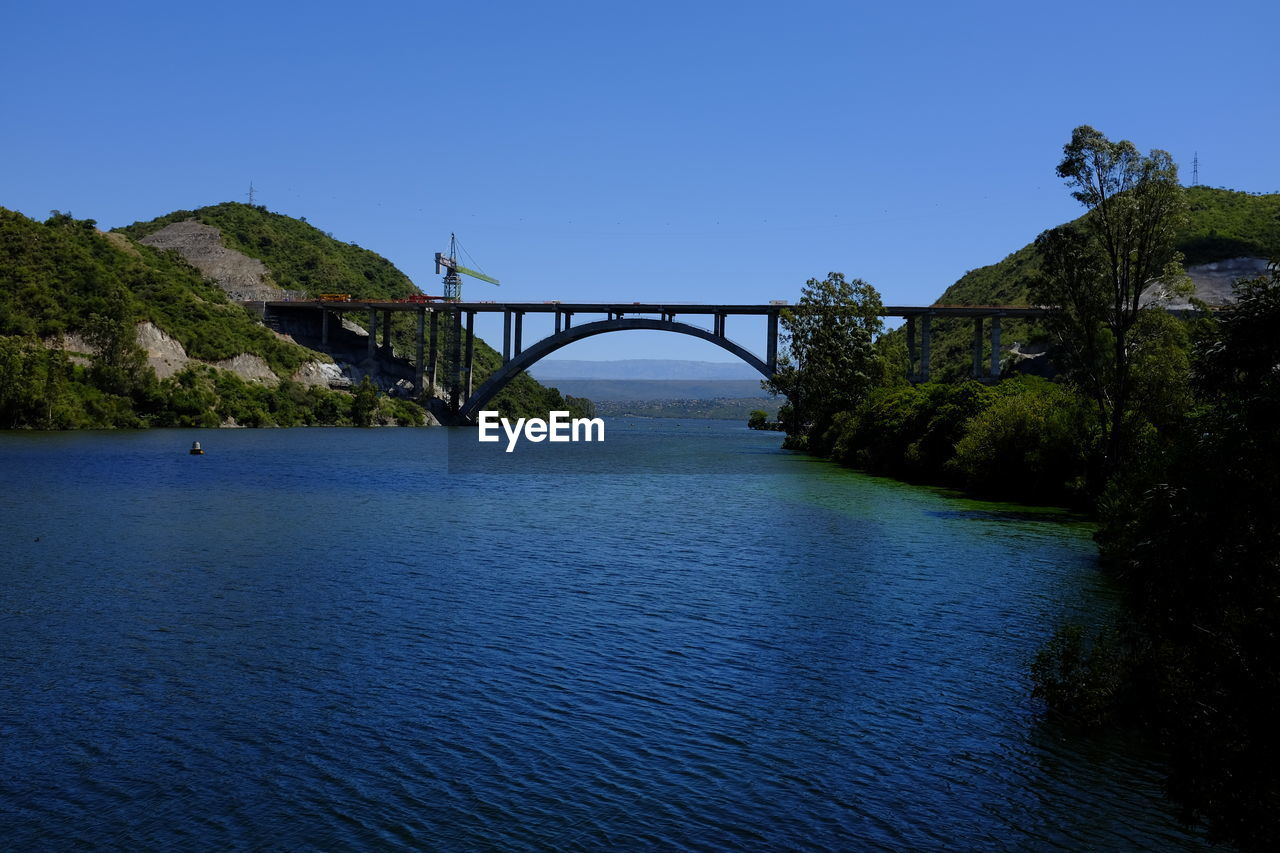 Bridge over river against clear blue sky