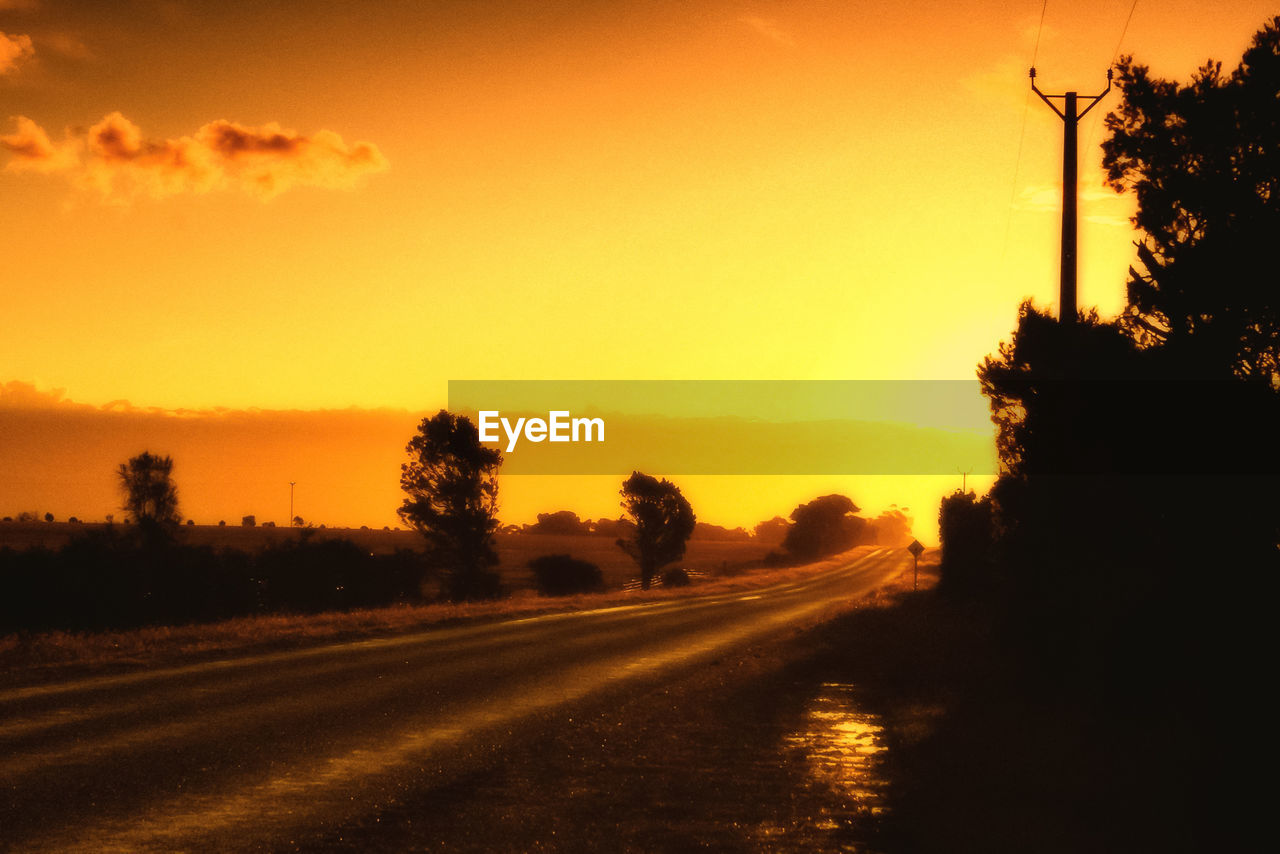 Road passing through trees during sunset