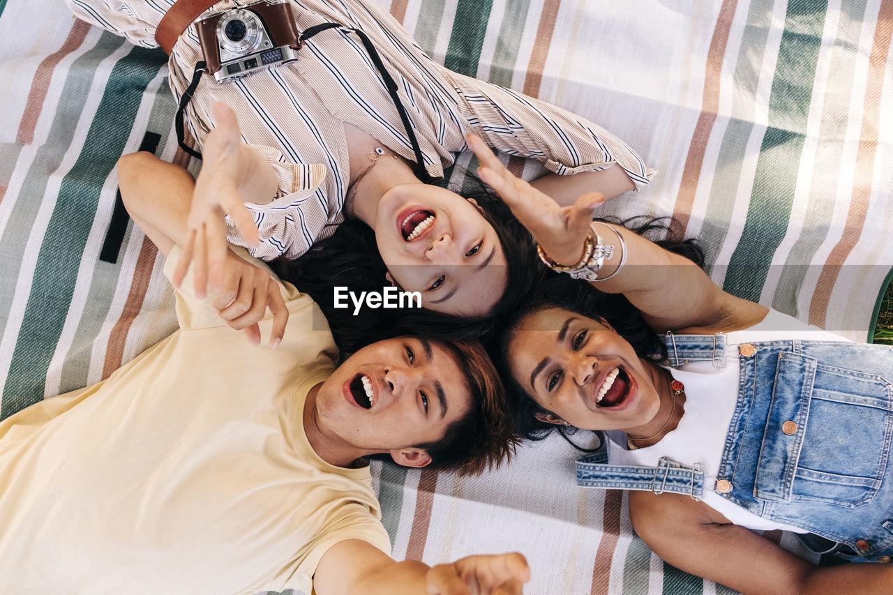 Friends screaming while relaxing on picnic blanket