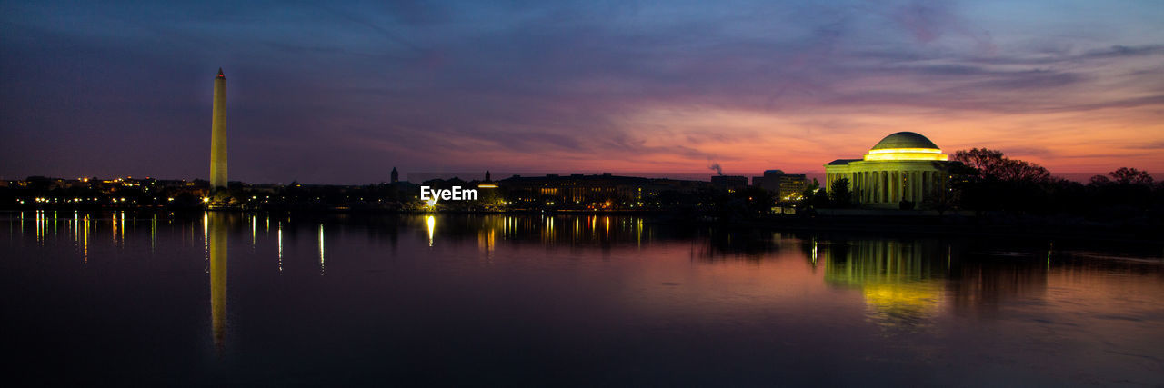 ILLUMINATED BUILDING BY LAKE AGAINST SKY AT NIGHT