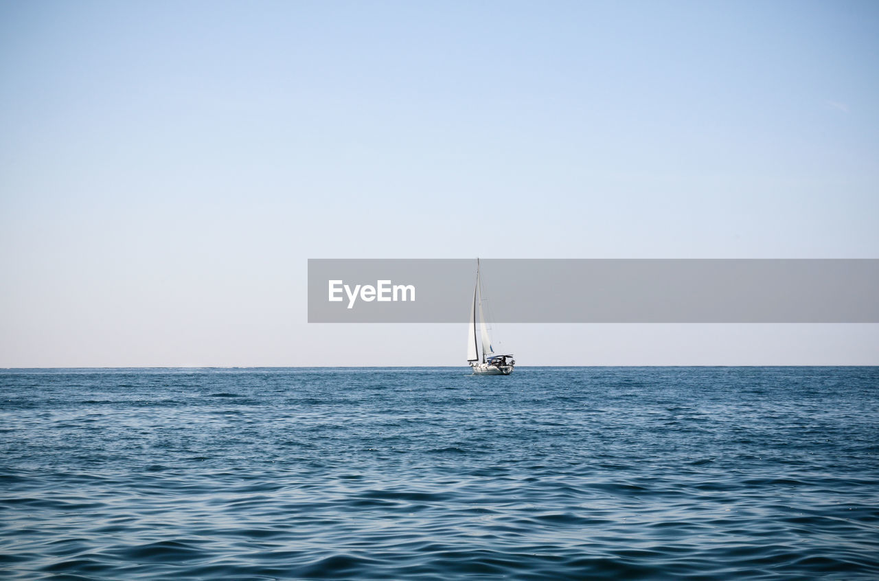 Sailboat sailing on sea against clear sky