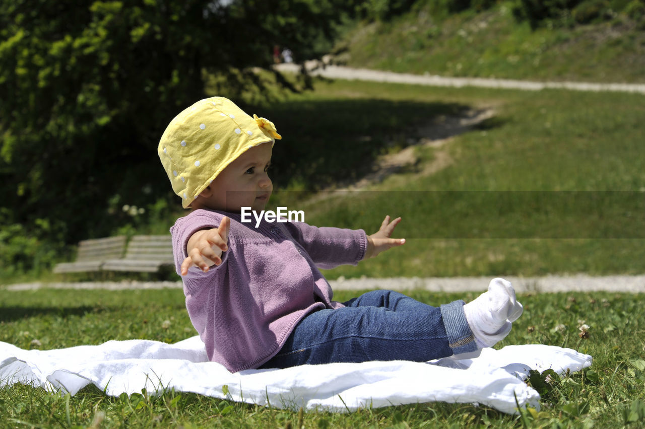 Side view of girl sitting on grass