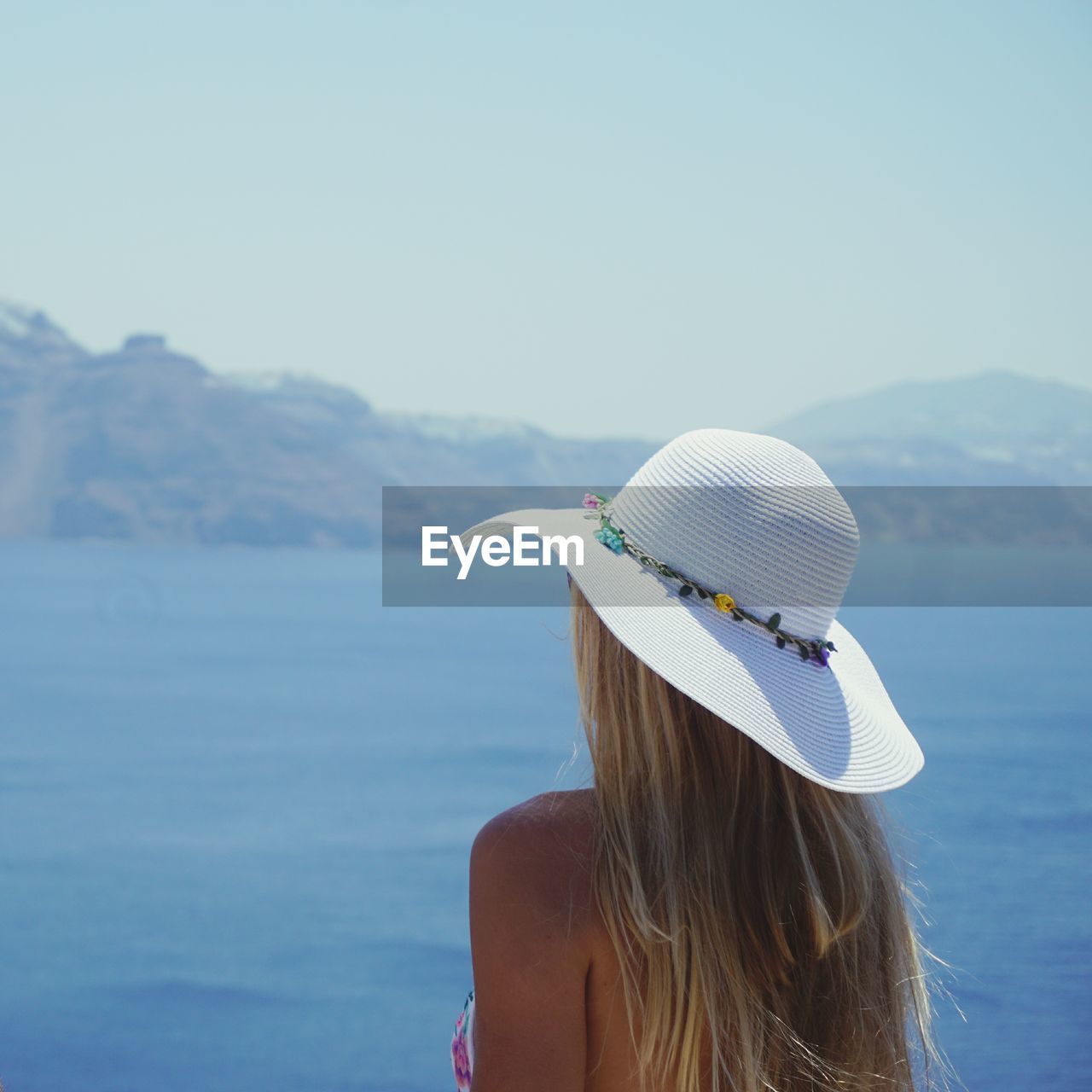 Rear view of woman wearing hat while looking at sea against sky