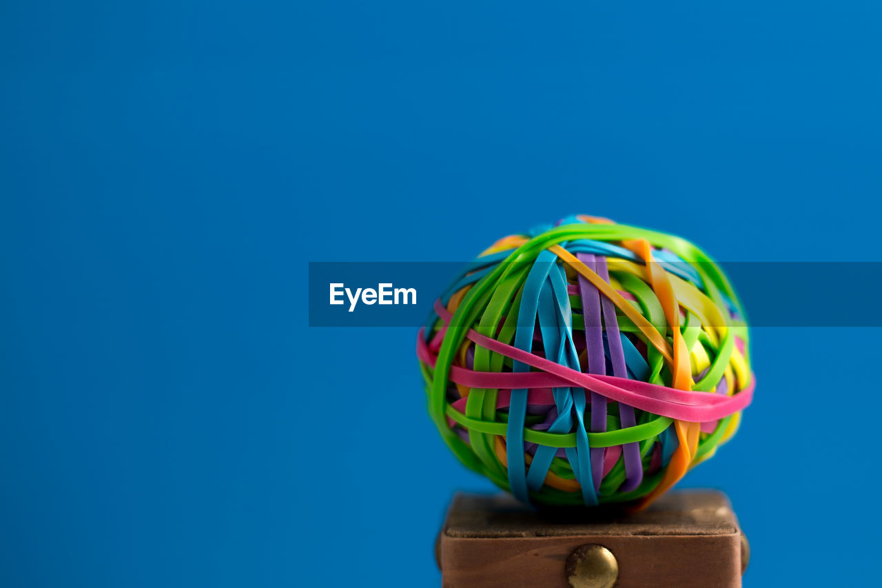 CLOSE-UP OF MULTI COLORED BALL AGAINST BLUE BACKGROUND