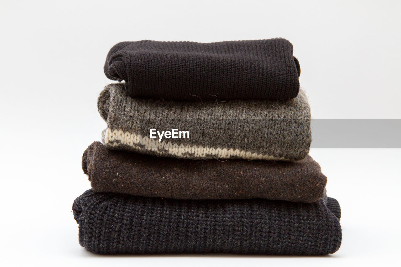 Stack of folded sweaters against white background