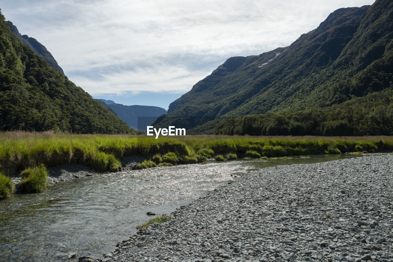 SCENIC VIEW OF STREAM BY MOUNTAINS AGAINST SKY