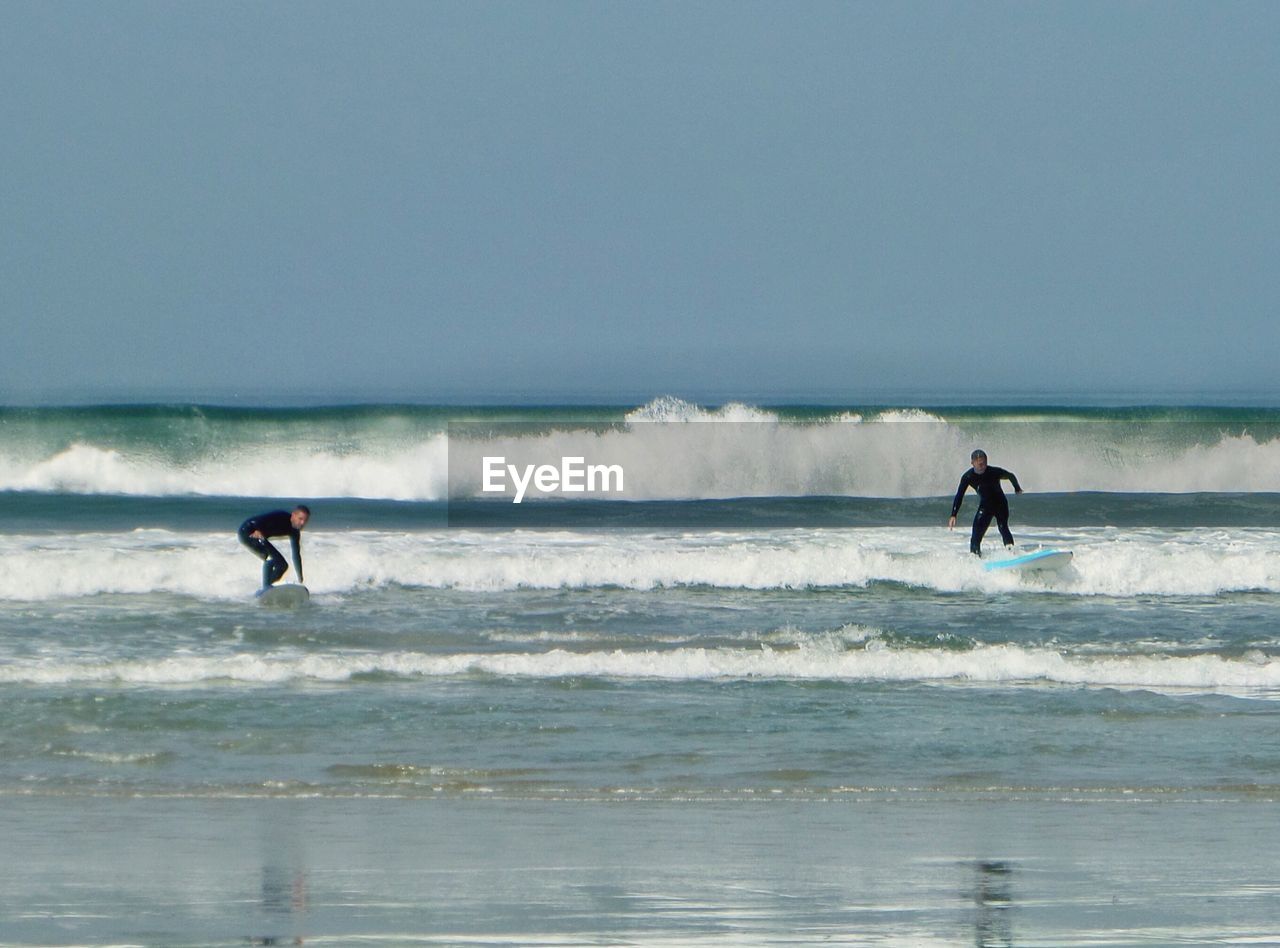 People surfing in sea against sky