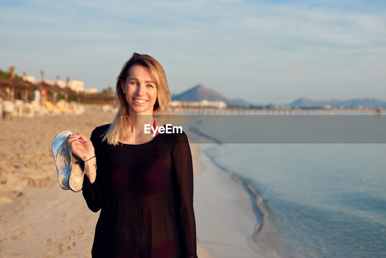 Portrait of smiling woman standing at beach