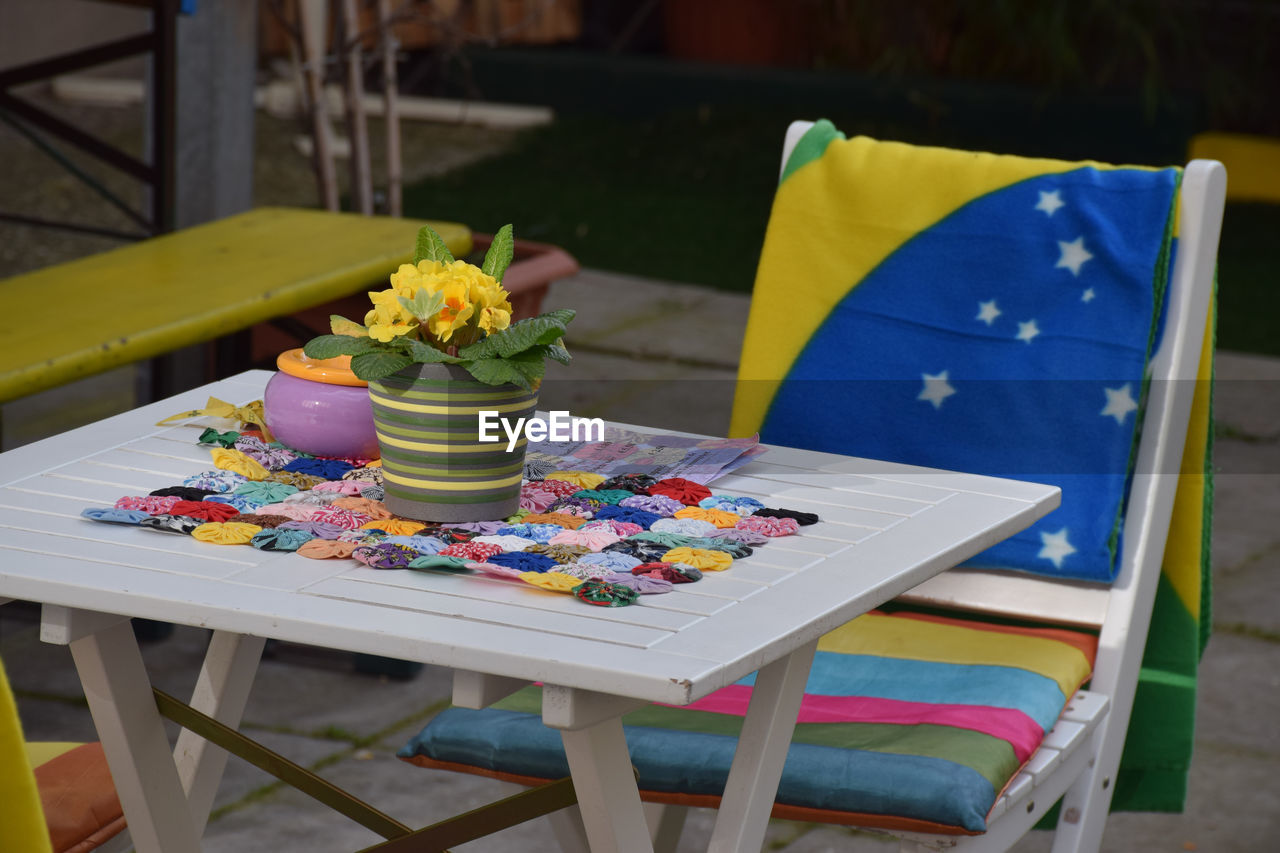 Flower pot on table by chair with brazilian flag in back yard