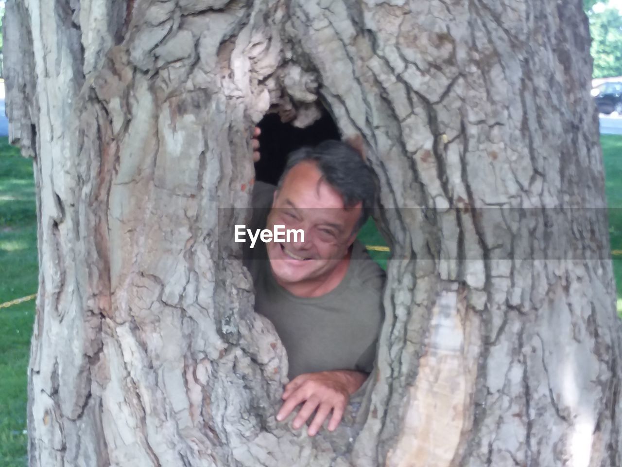 PORTRAIT OF SMILING MAN WITH TREE TRUNK