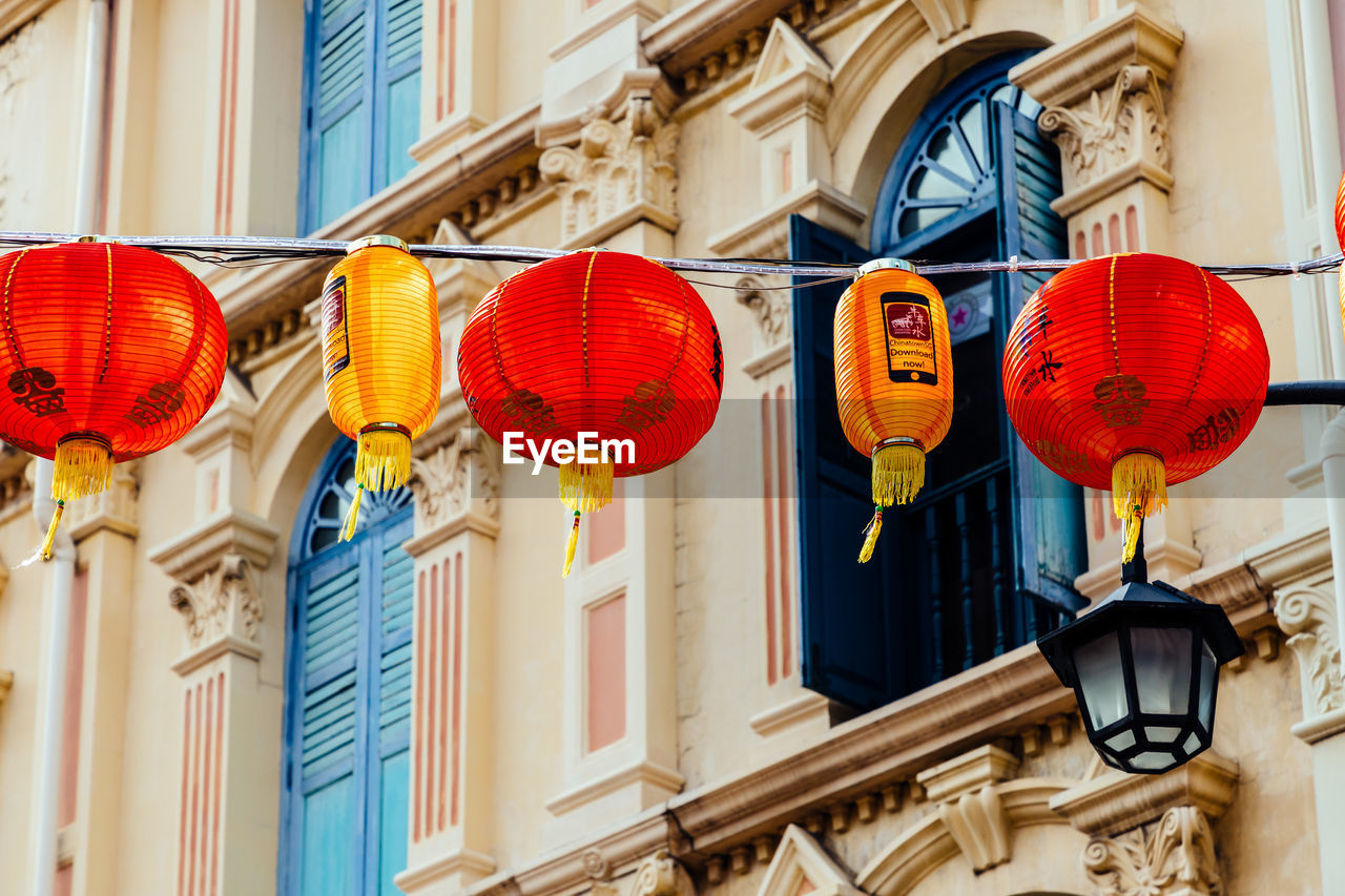 LOW ANGLE VIEW OF LANTERNS HANGING ON WALL