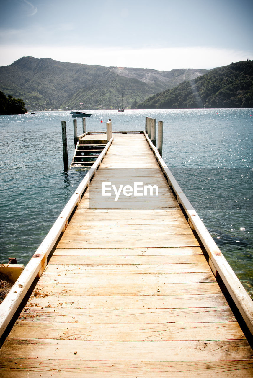 Wooden pier on jetty leading towards lake