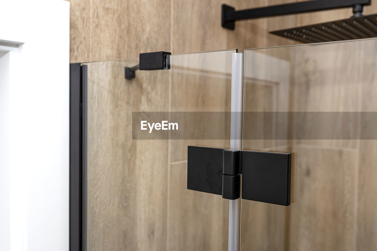 Black matt hinge connecting the wings of the shower enclosure flush with the glass, view from outsid