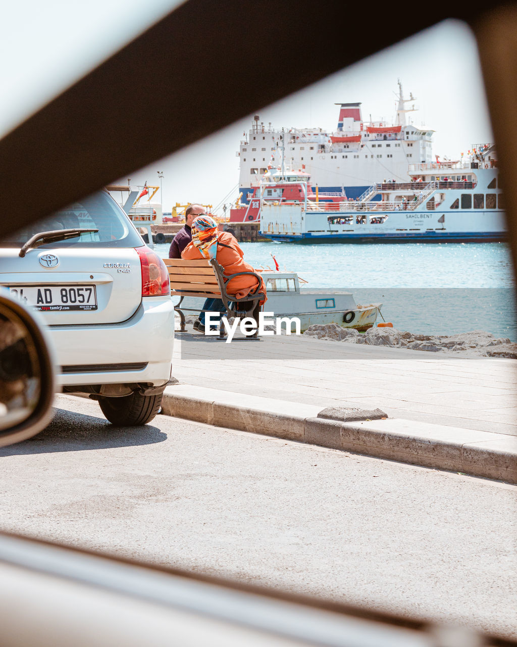 PEOPLE WORKING ON CAR BY CITY IN BACKGROUND