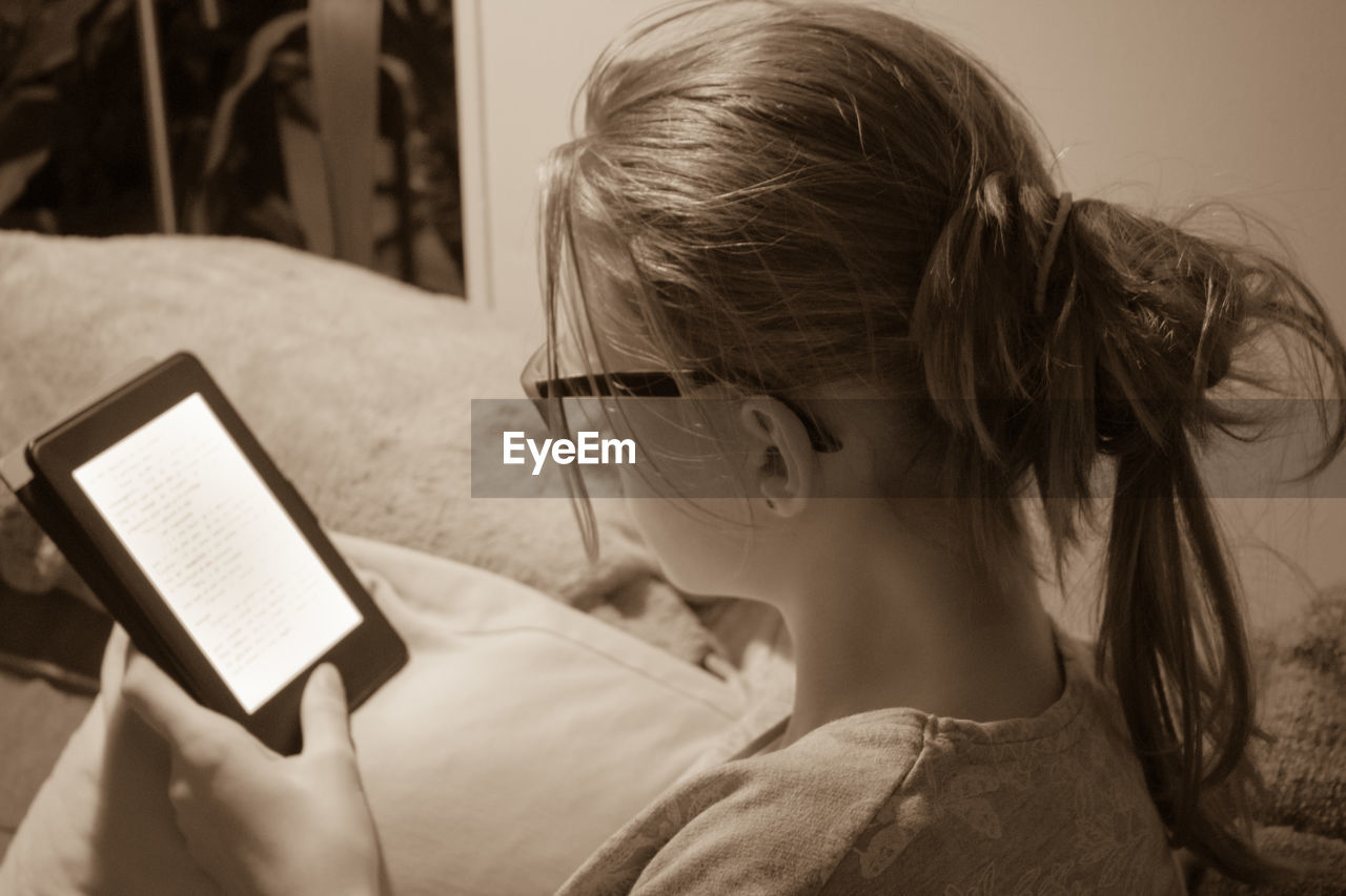 Close-up of woman using digital tablet while sitting on bed