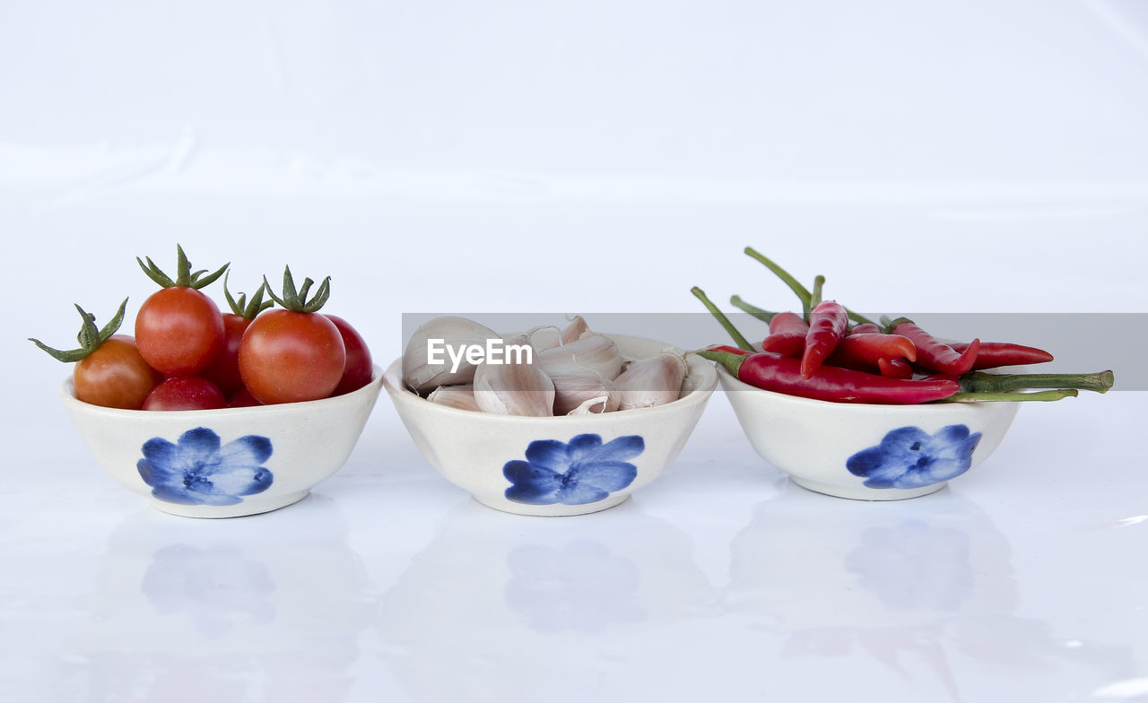 CLOSE-UP OF RED FRUIT OVER WHITE BACKGROUND