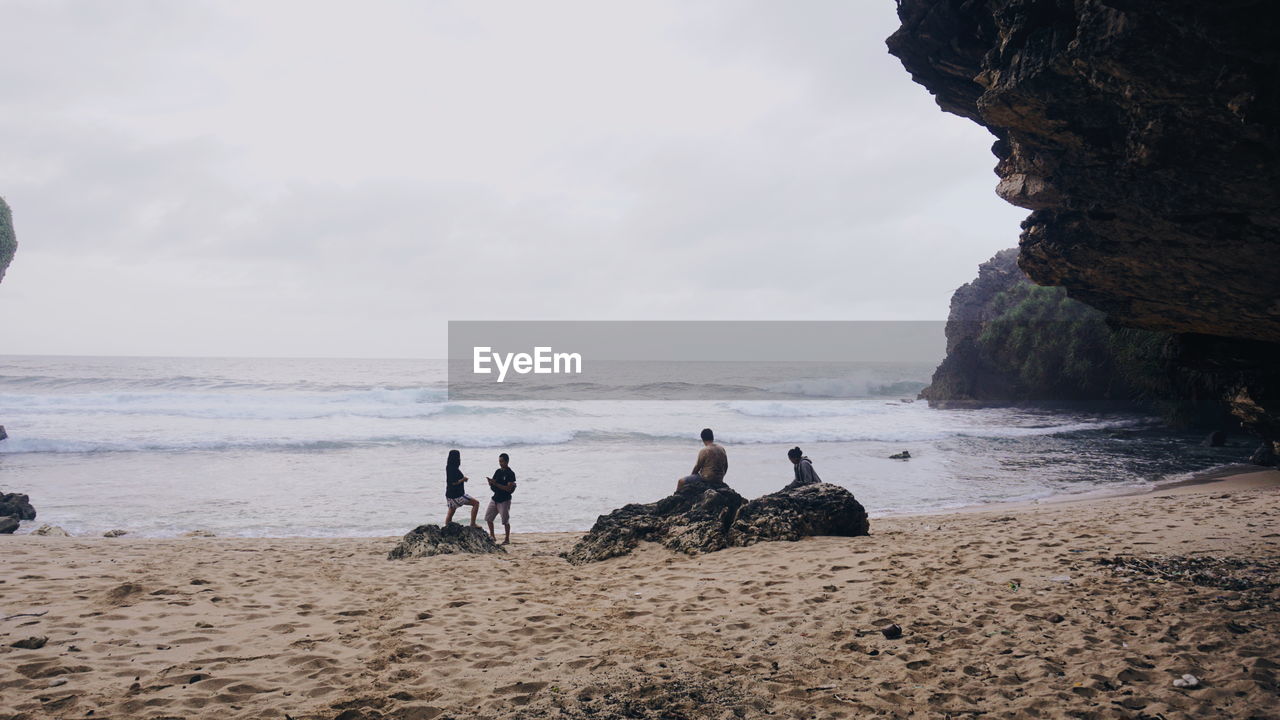 sea, beach, water, land, sky, coast, ocean, rock, shore, nature, body of water, horizon over water, group of people, beauty in nature, bay, horizon, sand, scenics - nature, cloud, wave, leisure activity, men, holiday, adult, day, trip, vacation, cliff, rock formation, tranquility, outdoors, women, tranquil scene, lifestyles, travel, non-urban scene