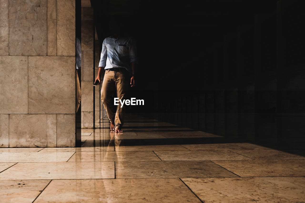 REAR VIEW OF MAN WALKING ON FLOOR