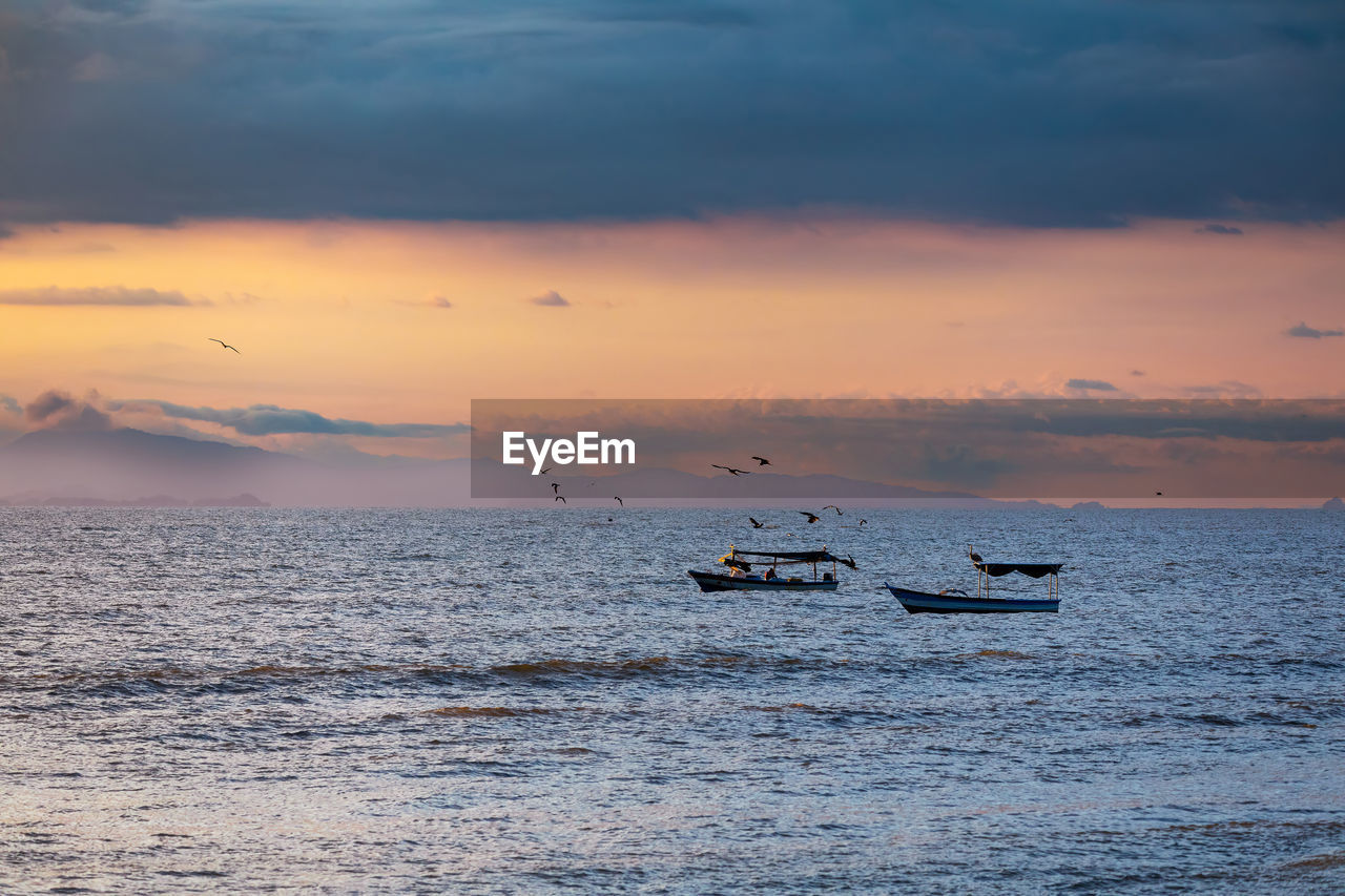 scenic view of sea against cloudy sky during sunset