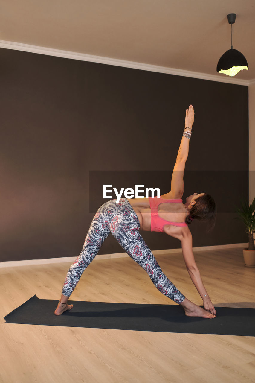 Young woman doing yoga on yoga mat in atmospheric yoga studio