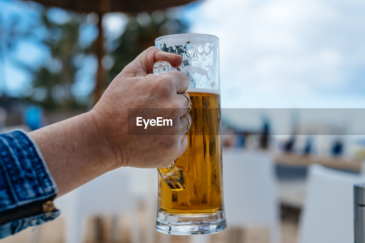 Close-up of hand holding beer glass