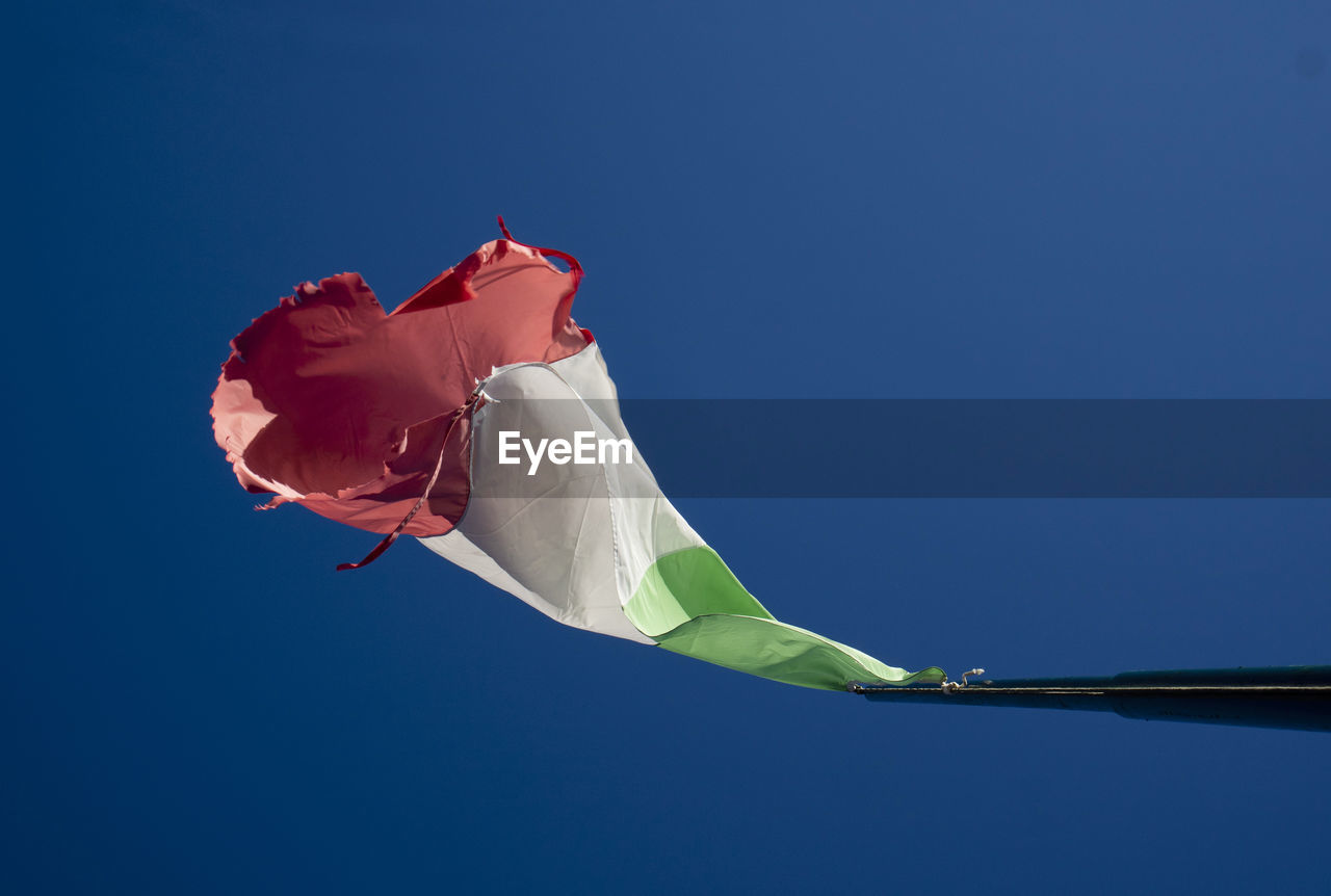 Low angle view of flag against clear blue sky
