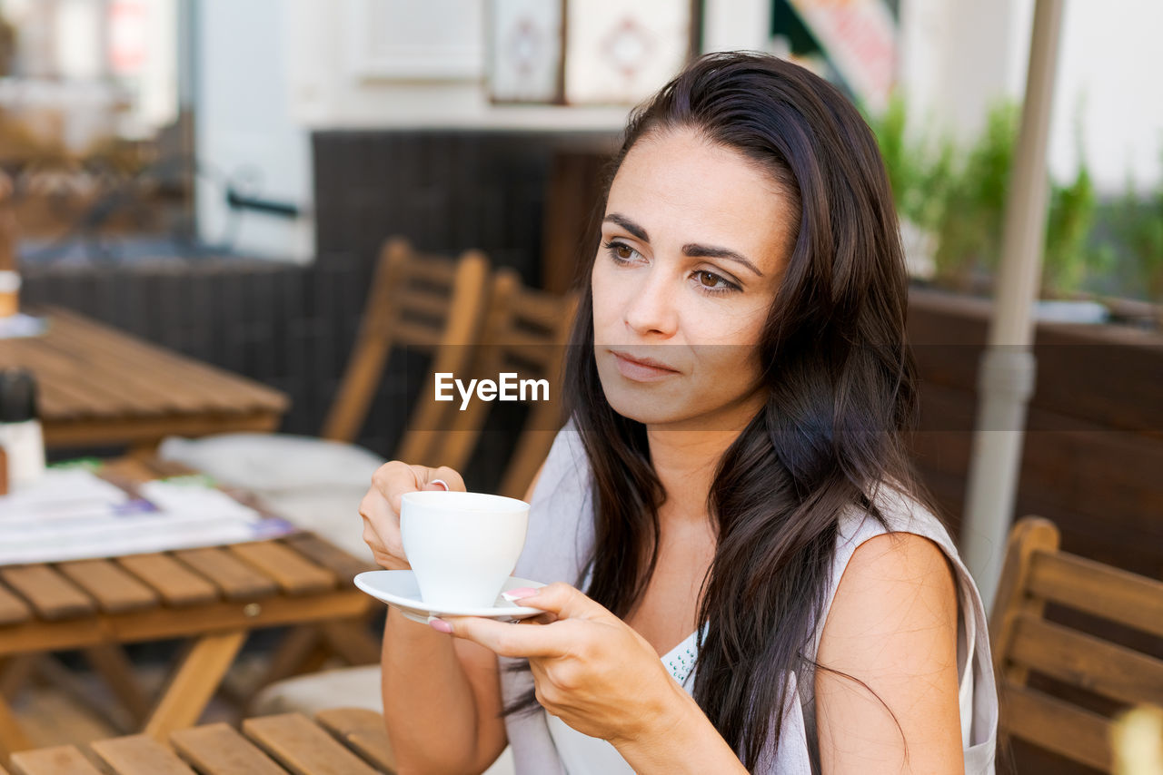 Positive business woman sitting in outdoor cafe drinking coffee.