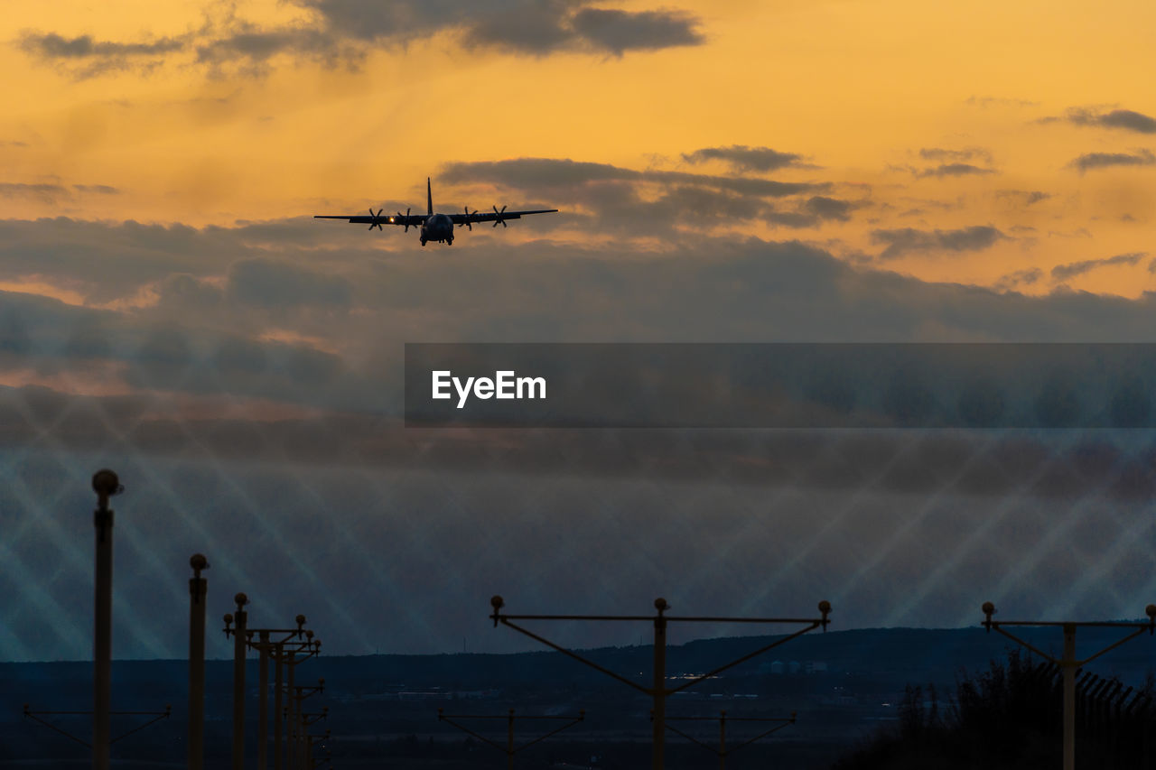 low angle view of airplane flying over sea against sky during sunset