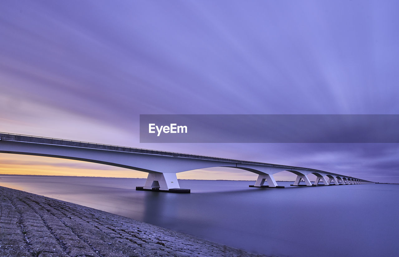 Low angle view of bridge over sea against sky. calm. sunset. soft colour. 