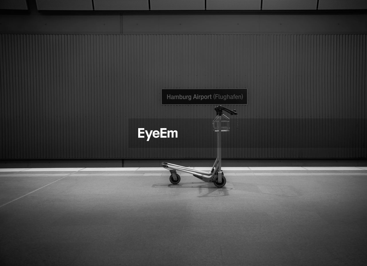 Trolley against placard on wall at hamburg airport