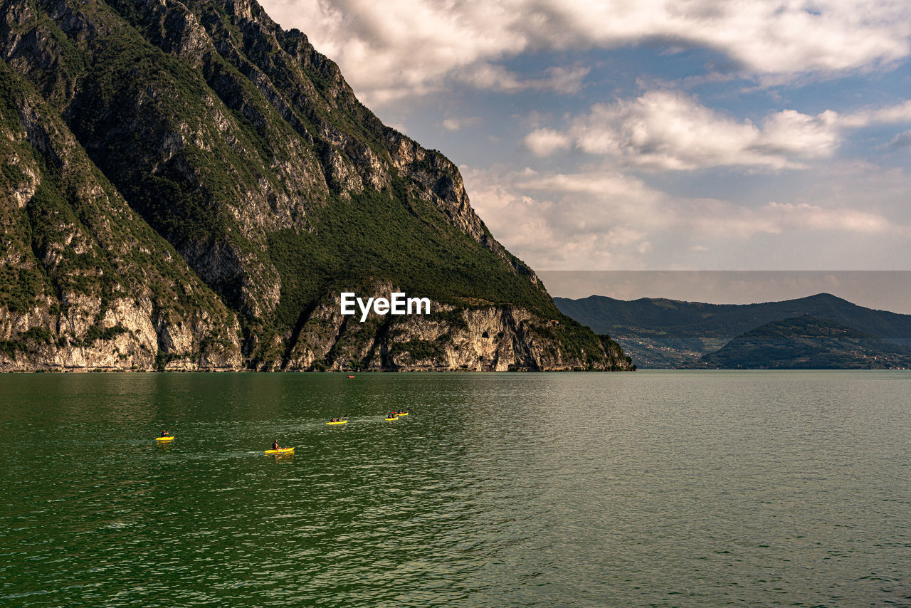 Scenic view of sea by mountains against sky