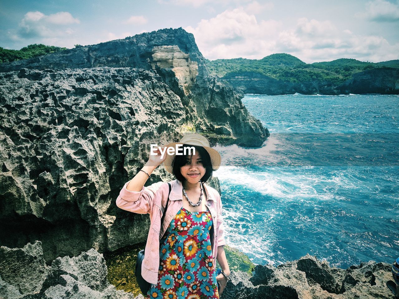 Portrait of woman standing on rock by sea