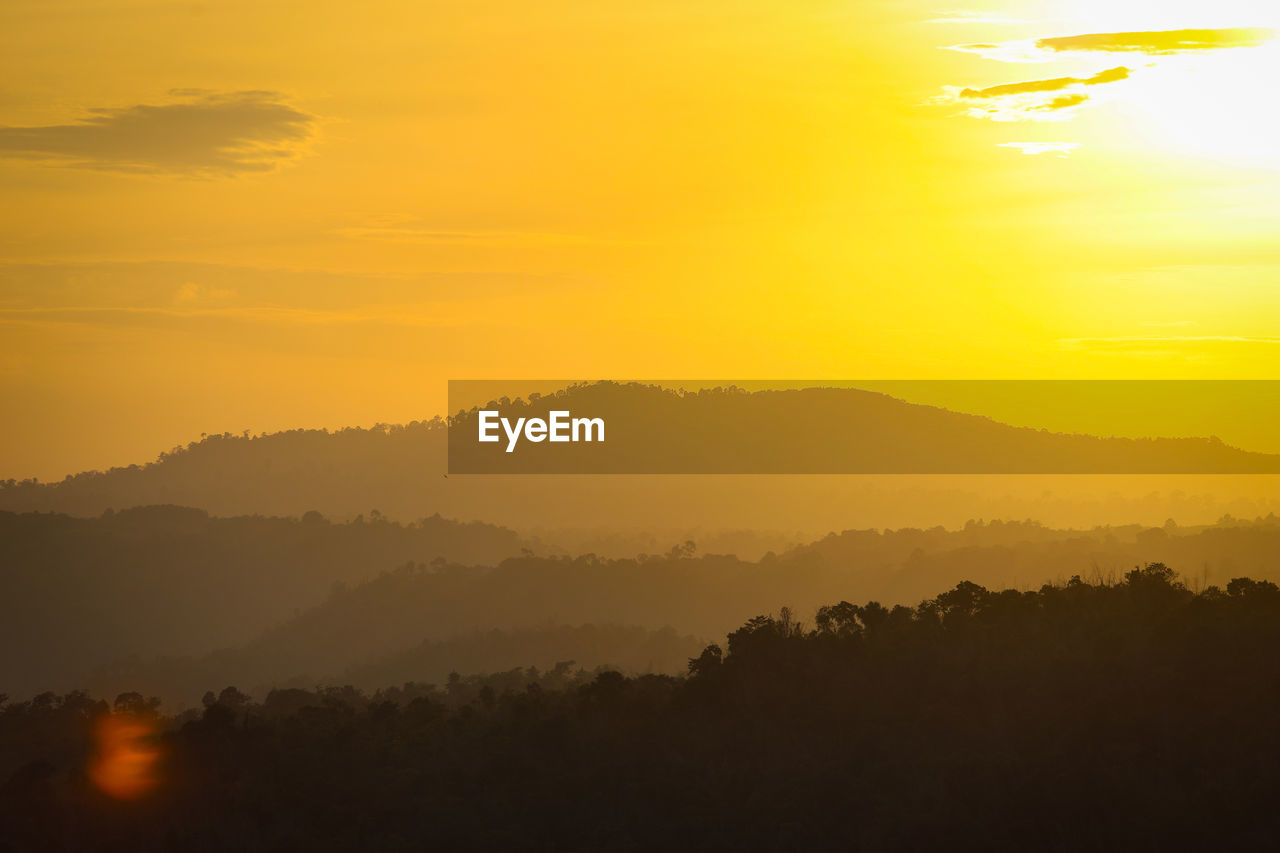 environment, sky, sunset, scenics - nature, landscape, beauty in nature, sun, mountain, fog, nature, tranquility, sunlight, dawn, tree, tranquil scene, land, cloud, silhouette, sunbeam, orange color, forest, yellow, no people, plant, idyllic, afterglow, mountain range, twilight, travel, horizon, outdoors, atmospheric mood, dramatic sky, travel destinations, non-urban scene, gold, tourism, evening, mist, rural scene, red sky at morning, summer, vibrant color, back lit, mountain peak, awe, vacation, trip, light - natural phenomenon, multi colored, backgrounds