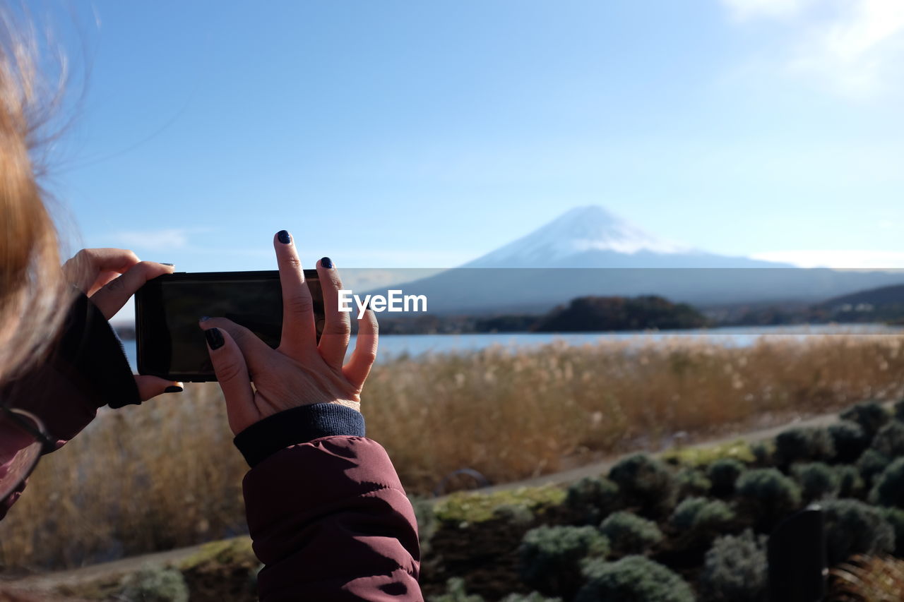 Cropped image of woman photographing river