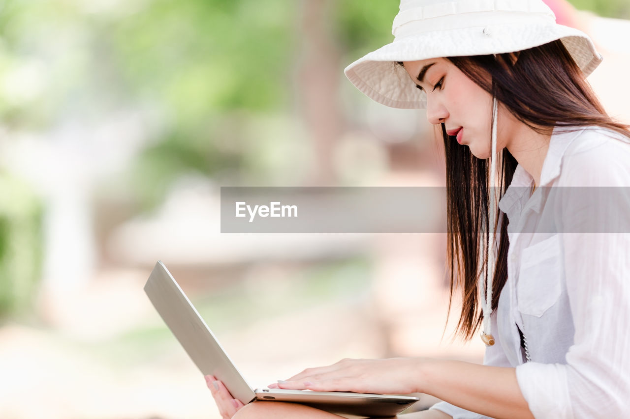 Side view of young woman using laptop