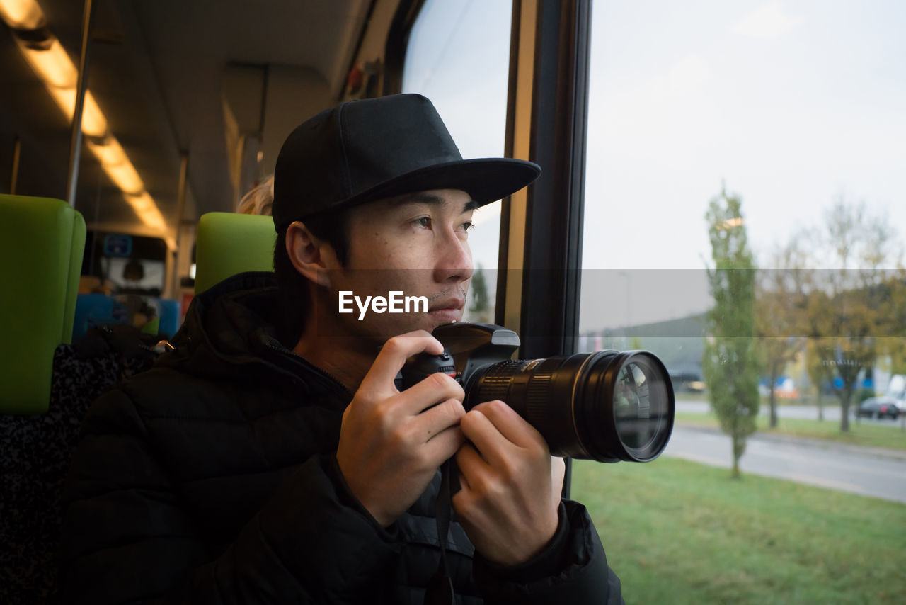 Close-up of man photographing while sitting in train