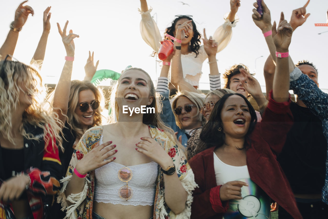 Happy men and women enjoying music at concert in summer